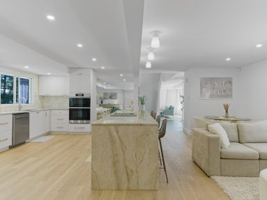 High-end bright kitchen with waterfall island leading to the living room with hardwood floors in Ottawa captured by Brandplayers.